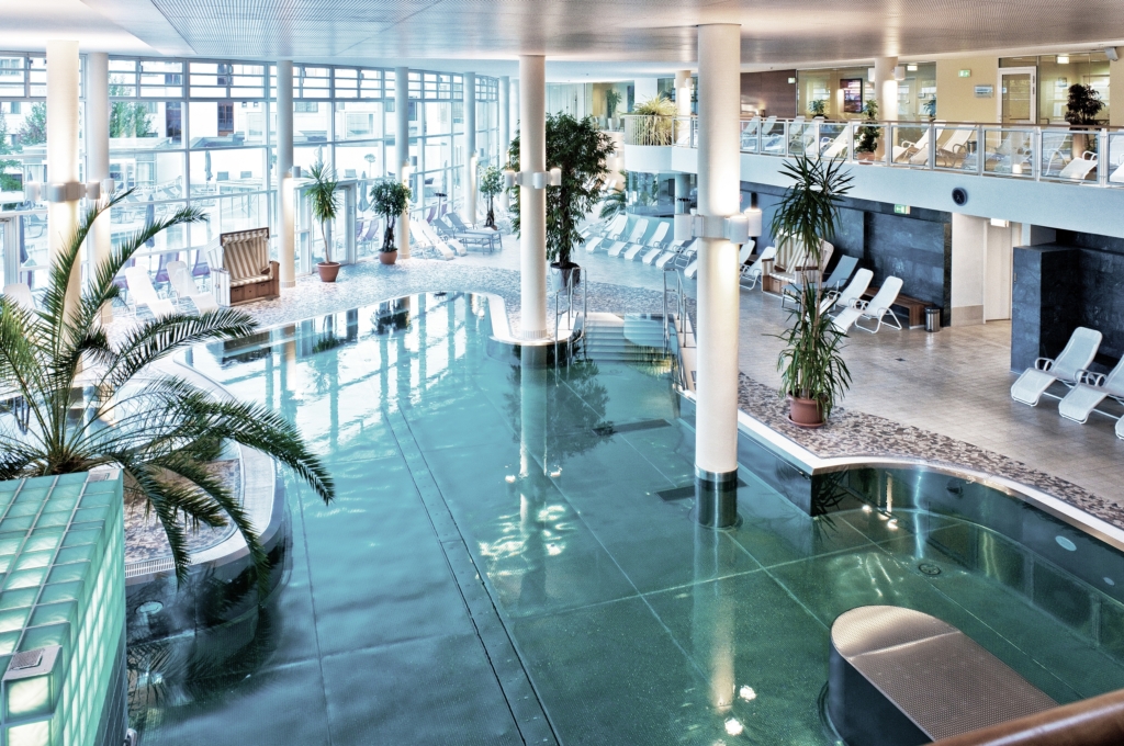 Bird's-eye view of the indoor thermal pool at REDUCE Hotel Vital with loungers surrounding it