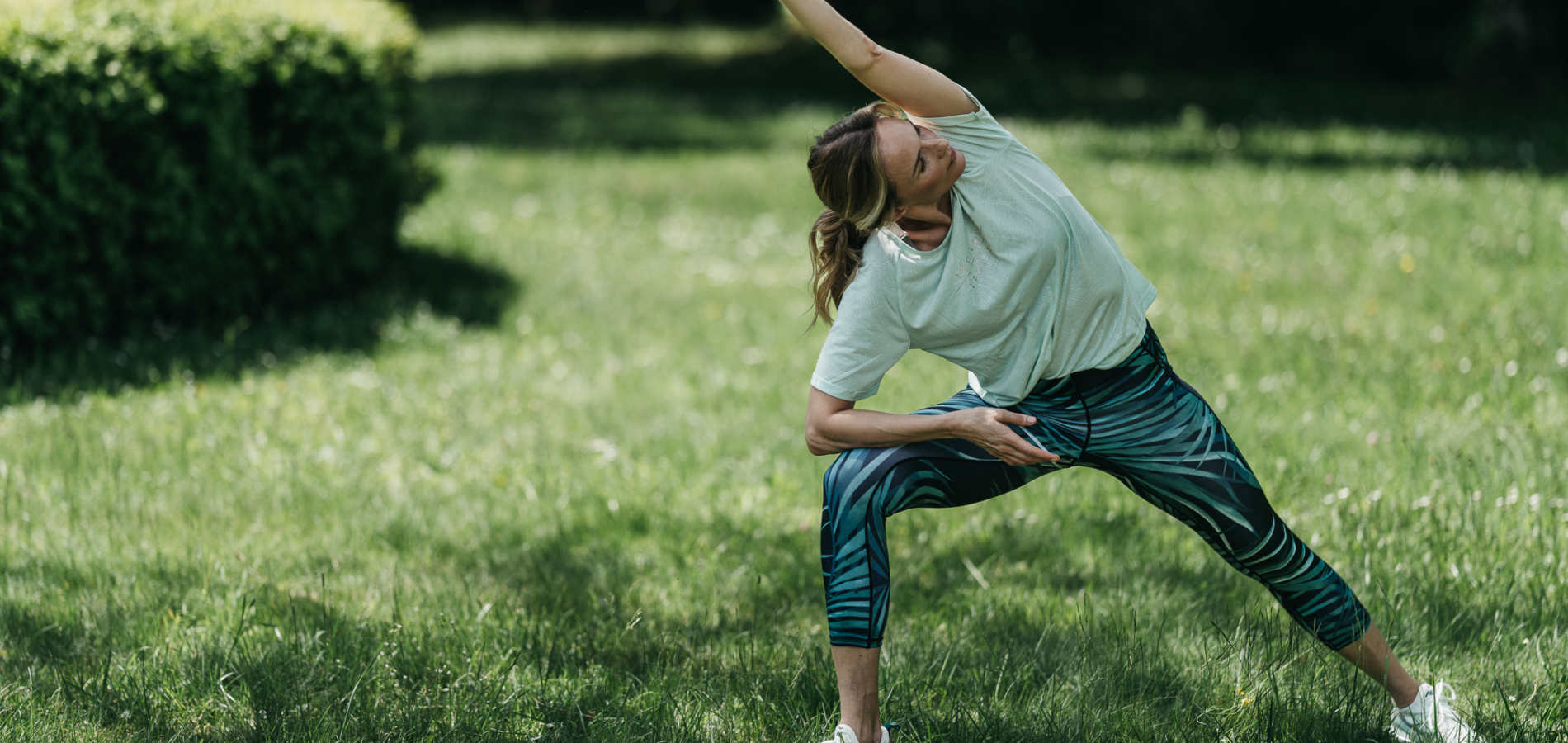 Frau bei einer Yoga-Übung im grünen Kurgarten des REDUCE Gesundheitsresorts Bad Tatzmannsdorf